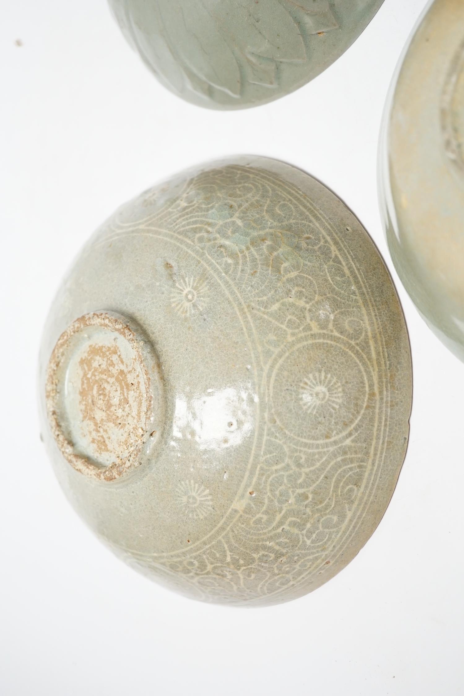 Two Korean celadon bowls, Goryeo dynasty (11th/12th century), the first carved with lotus petals to the underside, the second with fine crackle to the glaze, and a Korean slip-decorated celadon bowl (11th/12th century),